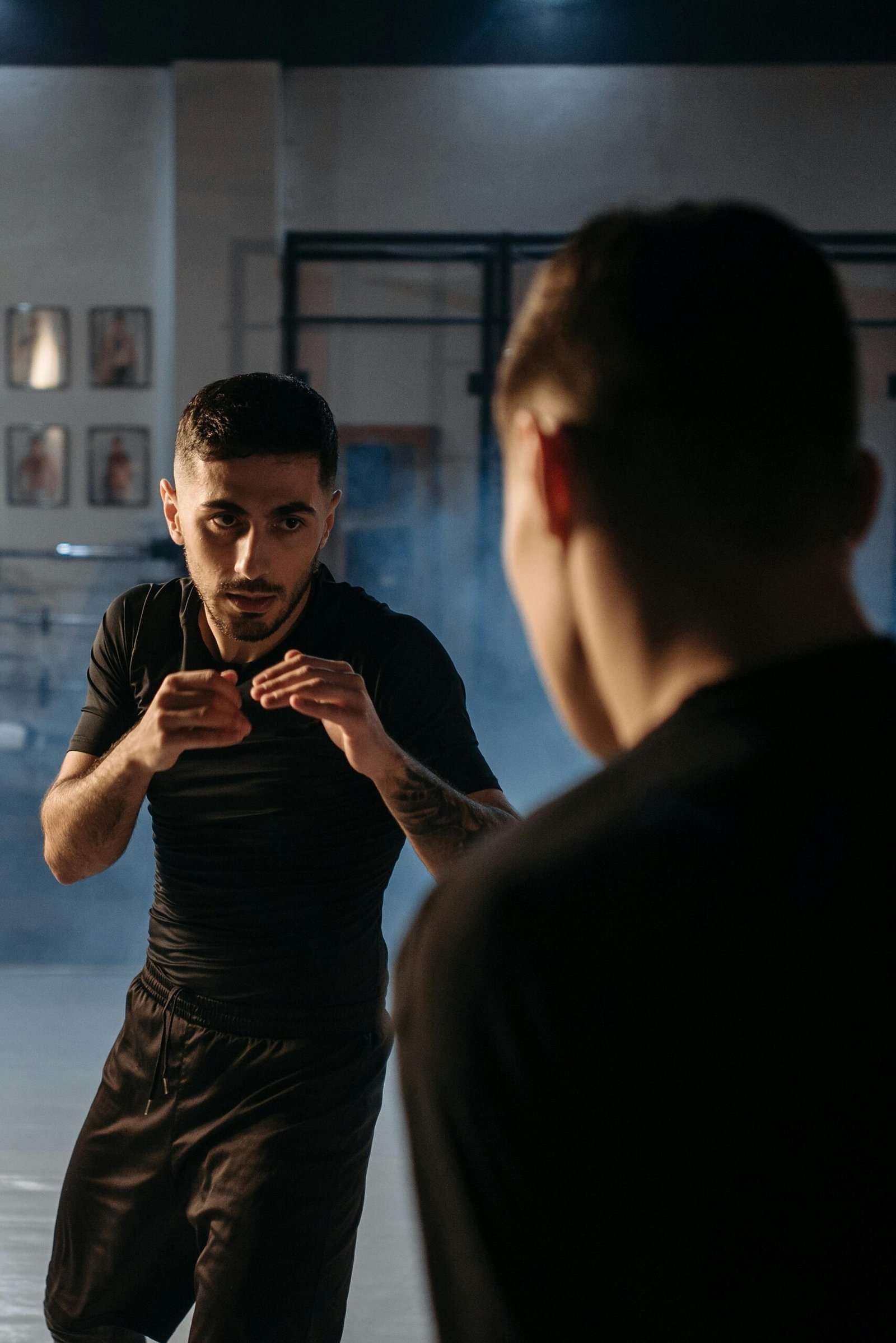 Focused men sparring during a boxing session in an indoor gym setting.