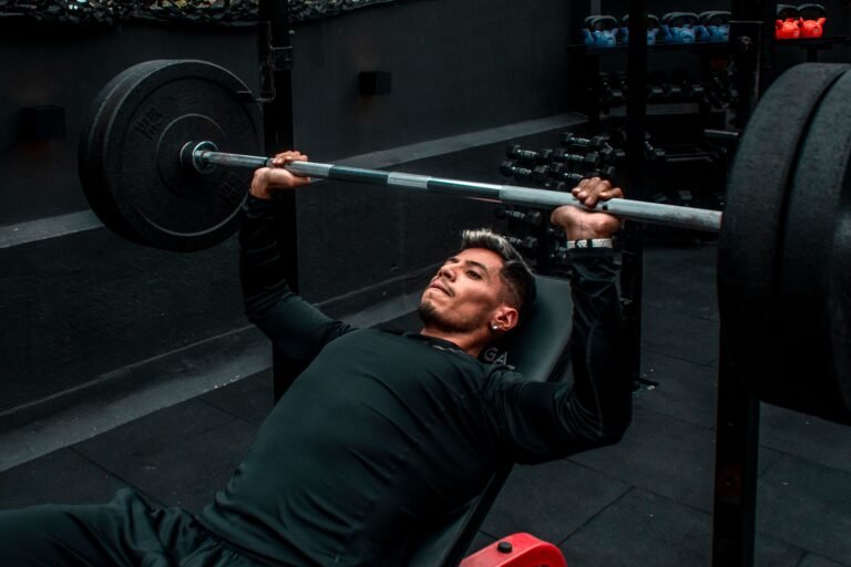 Man performing bench press with heavy barbell in a gym setting, focusing on strength training.