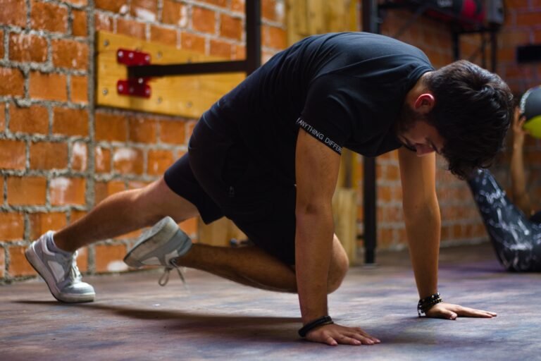 Man working out indoors, performing push-up exercise against a brick wall.
